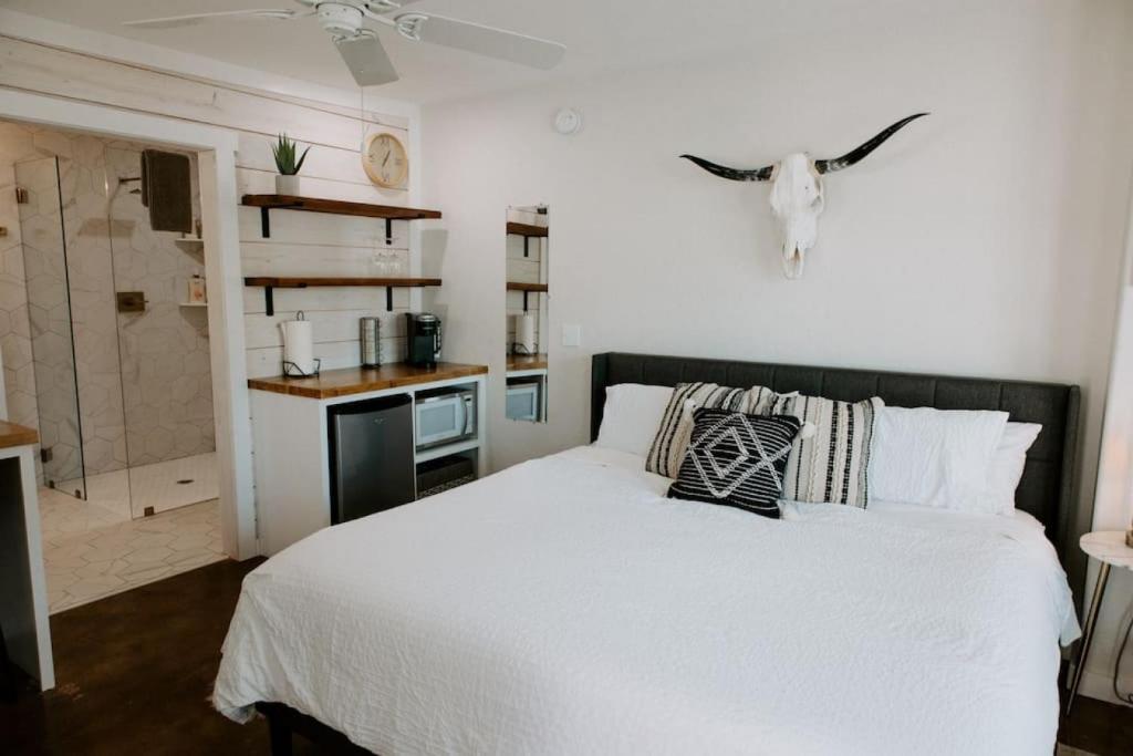 a bedroom with a white bed and a bathroom at Downtown Studio 3 at Beer Ranch Project Inn in Wimberley