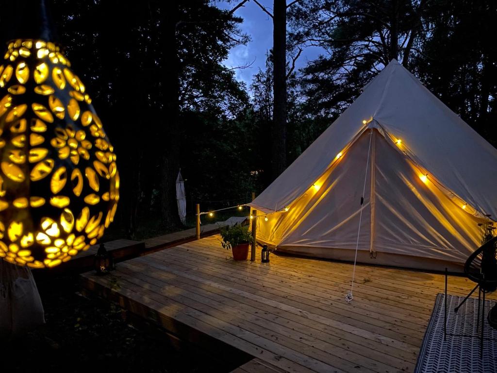 a tent with lights on a wooden deck at night at tent delhi a b&b in a luxury glamping style in Mariefred