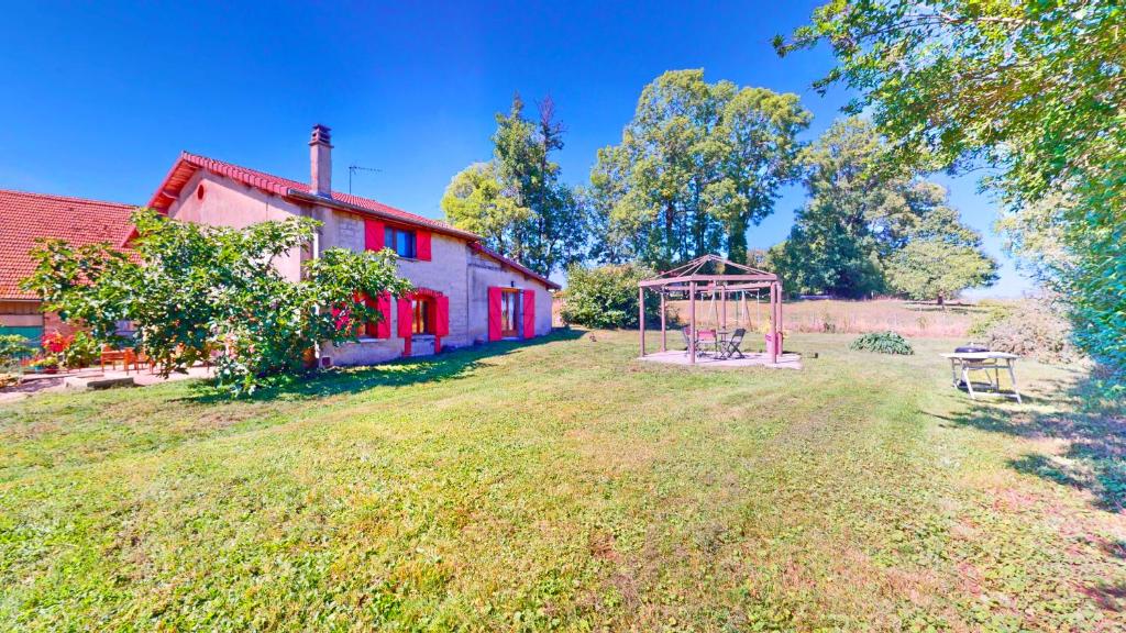 een rood huis met een speeltuin in de tuin bij Calme et chaleureux gîte de campagne. in Voiteur