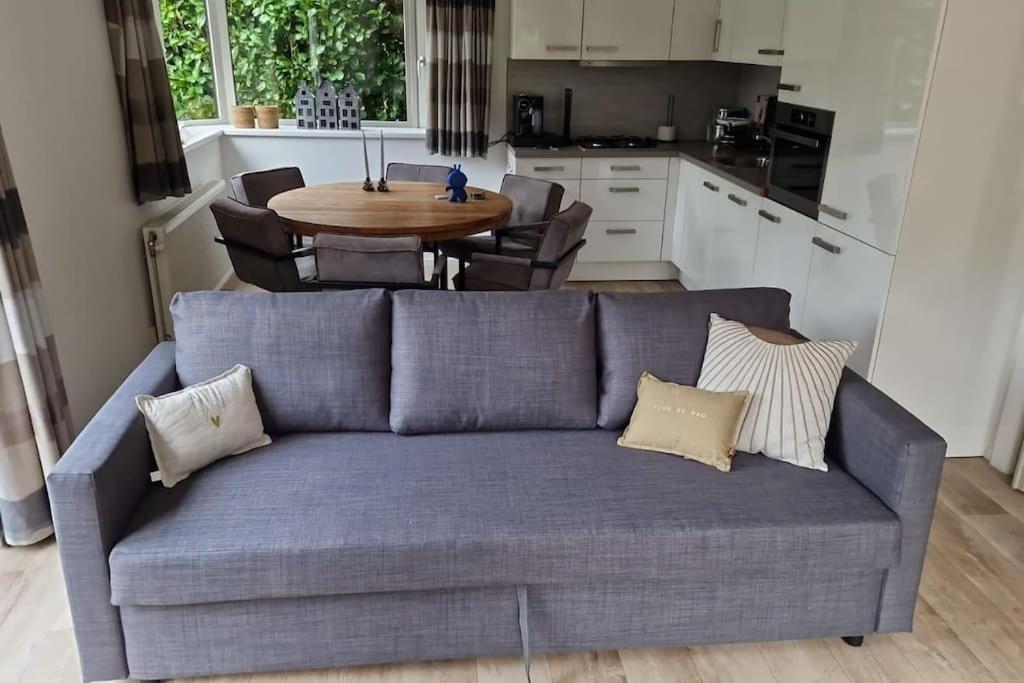 un sofá azul en una cocina con mesa en Luxe chalet met airco bij bos en zwemwater en Hoevelaken
