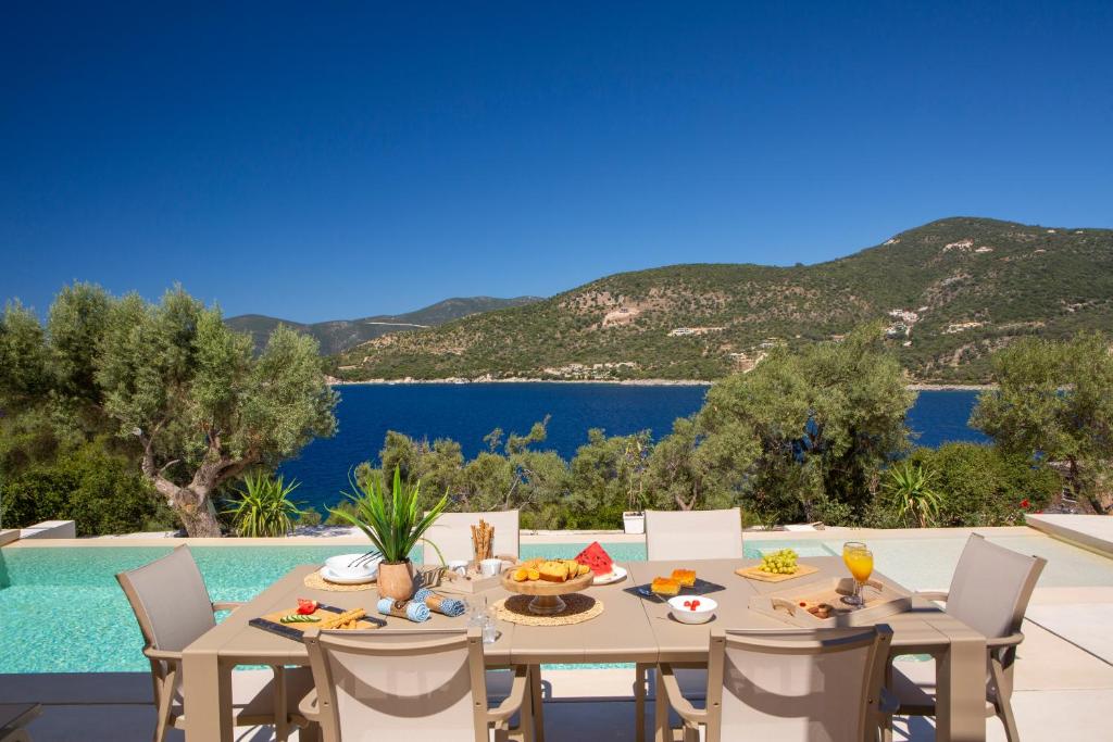 a dining table with a view of the water and mountains at Villa Mironi - Private sea access in Marantochori