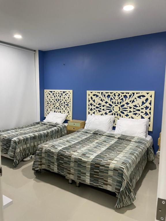 a bedroom with two beds and a blue wall at Apartamento Cartagena Morros Epic 23 in Cartagena de Indias