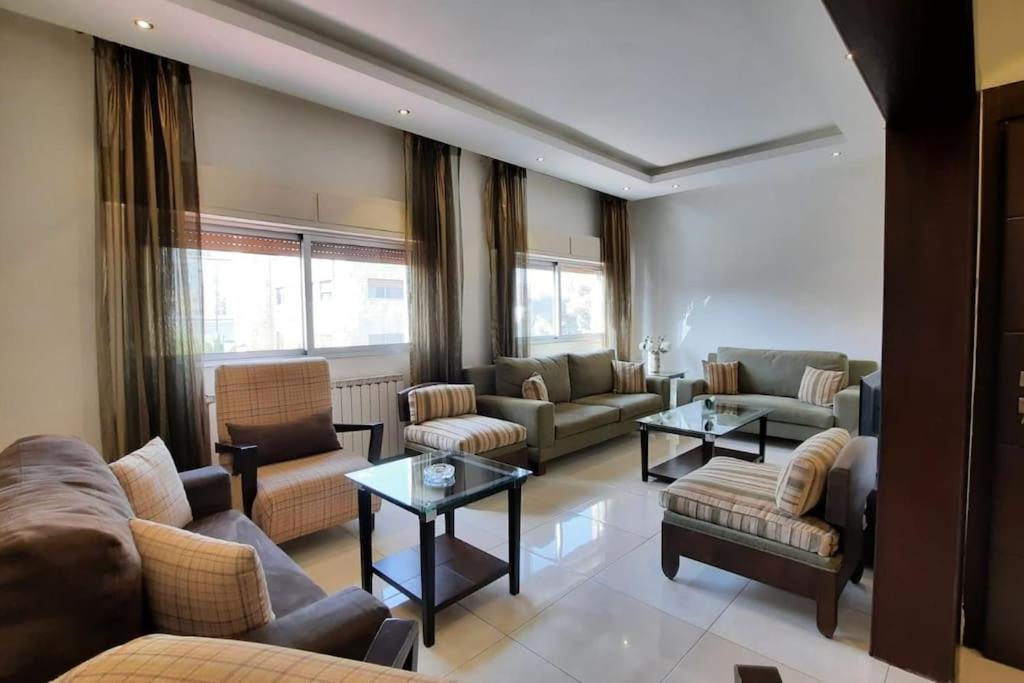 una sala de estar con sofás, sillas y mesas. en Two bedroom furnished apartment in Amman near Boulevard Abdali. en Amán