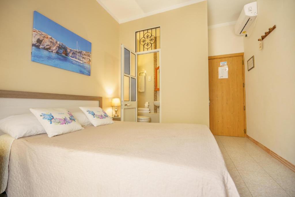 a bedroom with a large white bed with two pillows at Lantern Guest House in Marsalforn