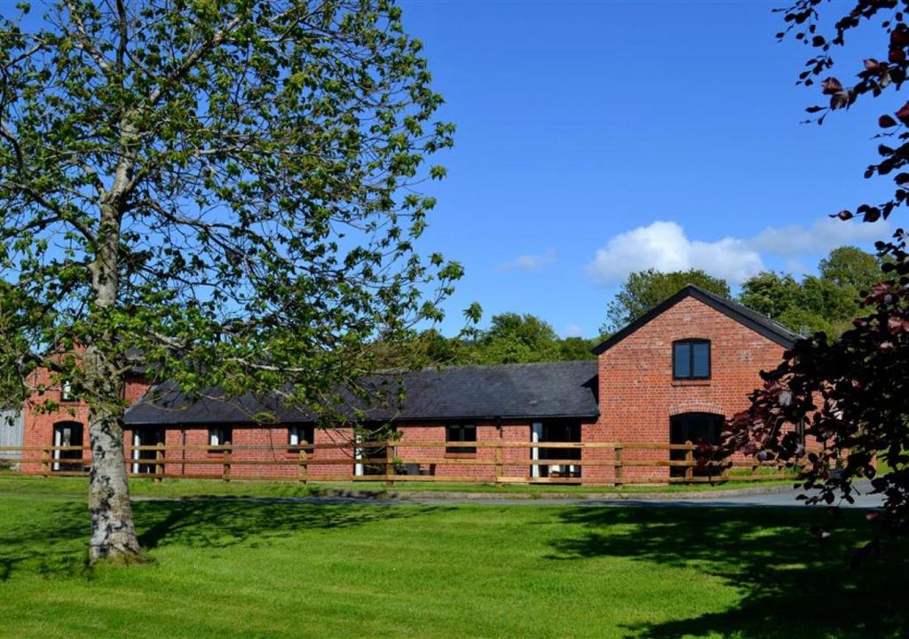 a red brick barn with a black roof at Y Beudy in Llandinam