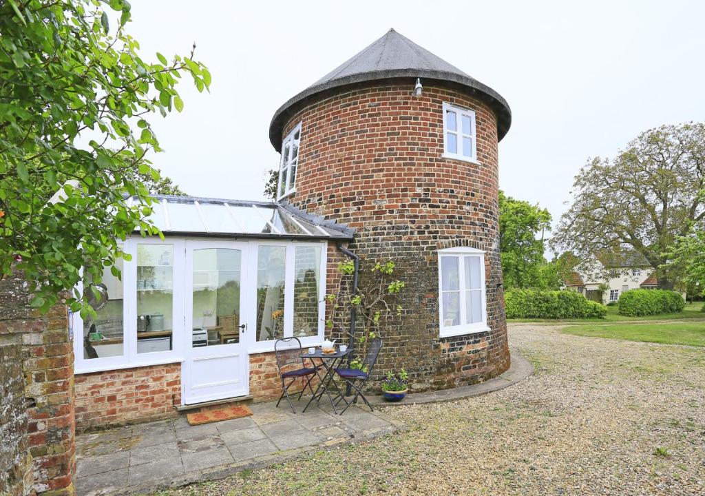 a brick house with a round window and white doors at Sampson's Mill in Wickham Market