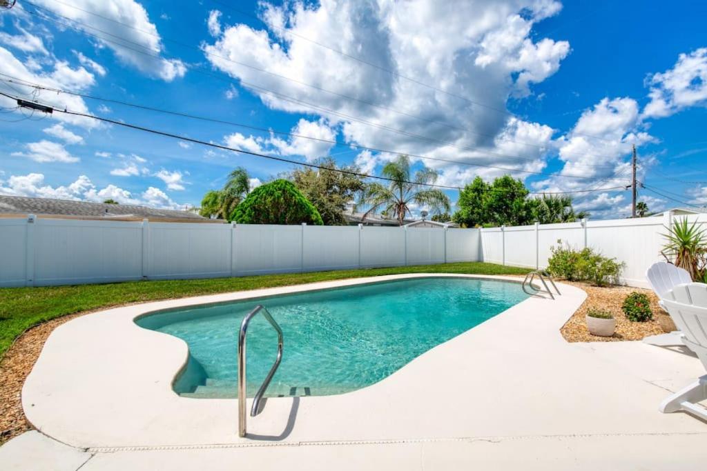 a swimming pool in a yard with chairs and a fence at Tropical Vibes Bungalow with Pool in Ormond Beach