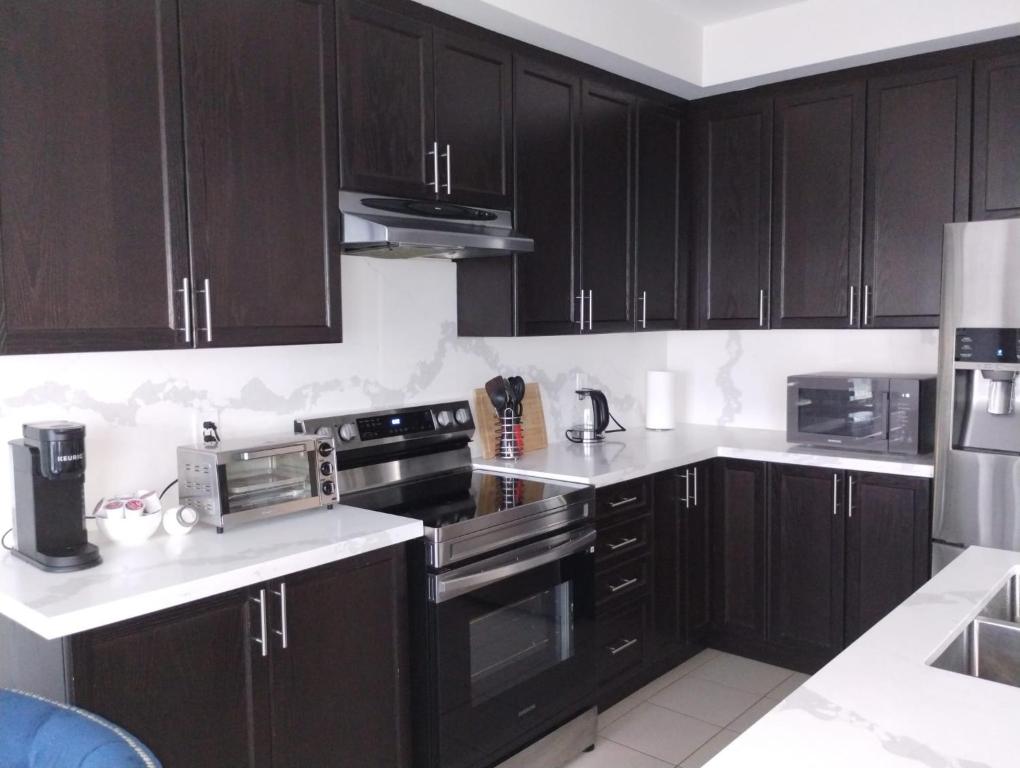 una cocina con armarios de madera oscura y electrodomésticos negros en luxurious 3-bedroom residential home in Lincoln en Beamsville