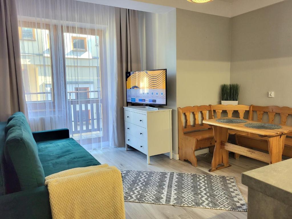 a living room with a couch and a table with a television at Apartament ORKAN przy Krupówkach in Zakopane