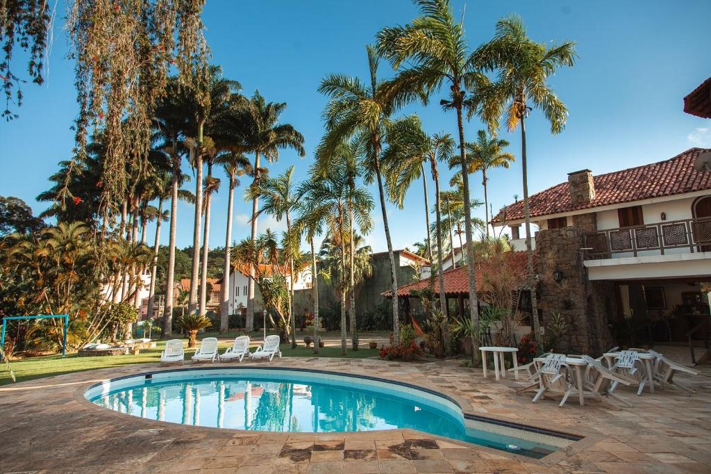 una piscina en un patio con palmeras en Mansão Residence & Club en Vassouras