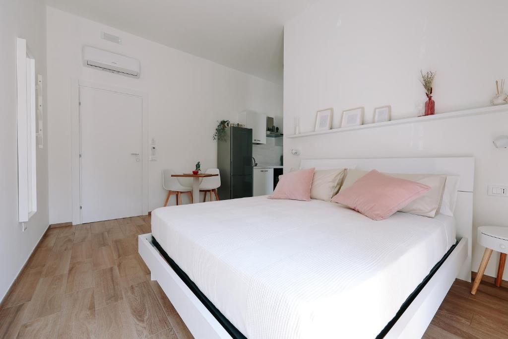 Dormitorio blanco con cama blanca y almohadas rosas en PRIMO RENT ROOM, en Mesagne