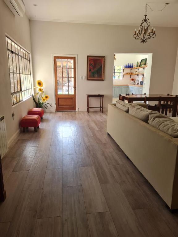een woonkamer met een bank en een houten vloer bij Lechuza del Campanario in San Antonio de Areco