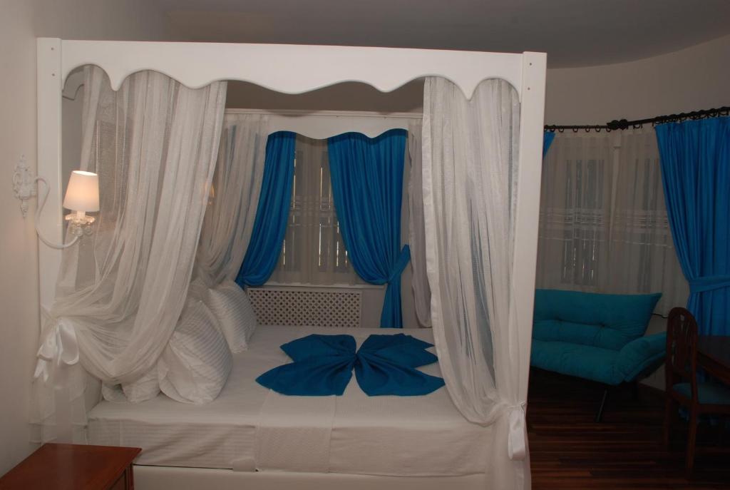 a bedroom with a white bed with blue curtains at Mavi Inci Park Otel in Erdek