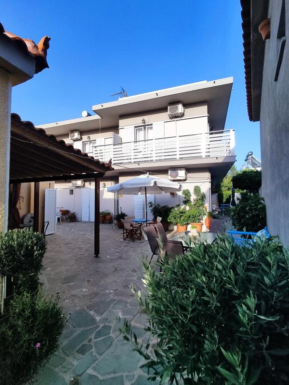 a building with a patio with an umbrella and chairs at Maria Pantermou Rooms in Skala Eresou