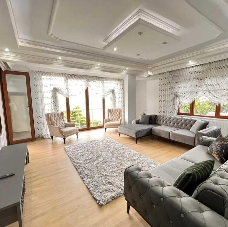 uma grande sala de estar com sofás e um tapete em Denize Sıfır 2 Yatak Odalı ve 2 Çekyatlı Bahçeli Ev - Seafront, 2 bedroom, 2 sofa bed house with big garden em Rize