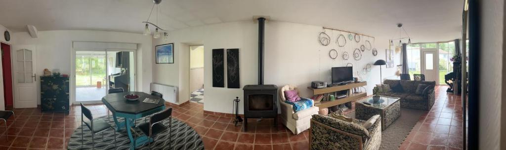 een woonkamer met een bank, een tafel en een tv bij la maison d'hôtes des Charentes in Les Touches-de-Périgny