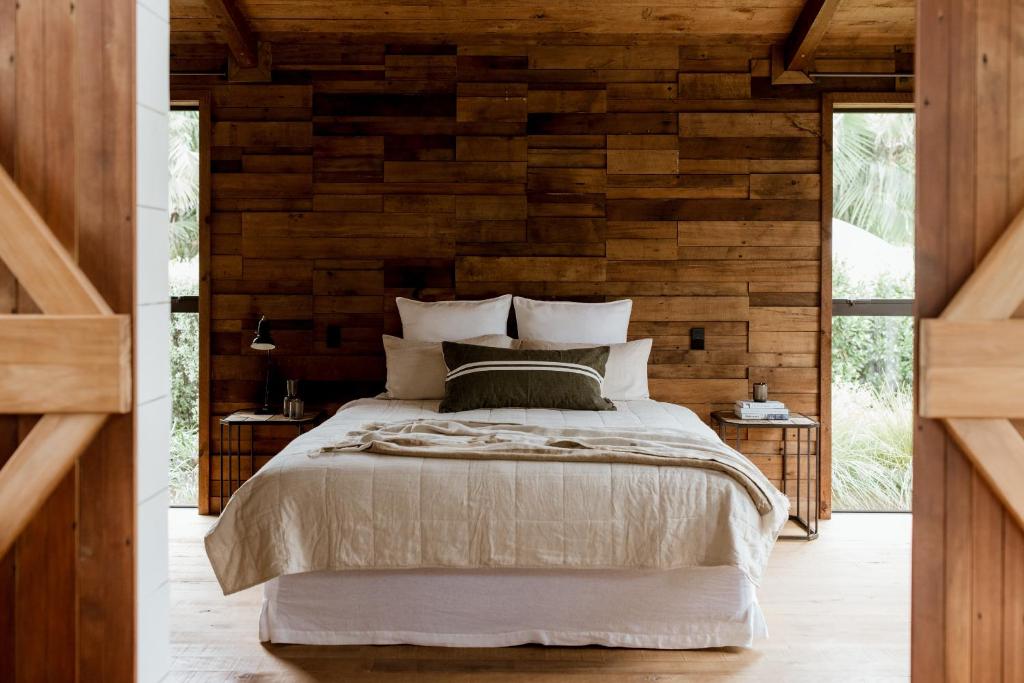 1 dormitorio con 1 cama y pared de madera en The Villa at Bali Garden Matakana, en Omaha