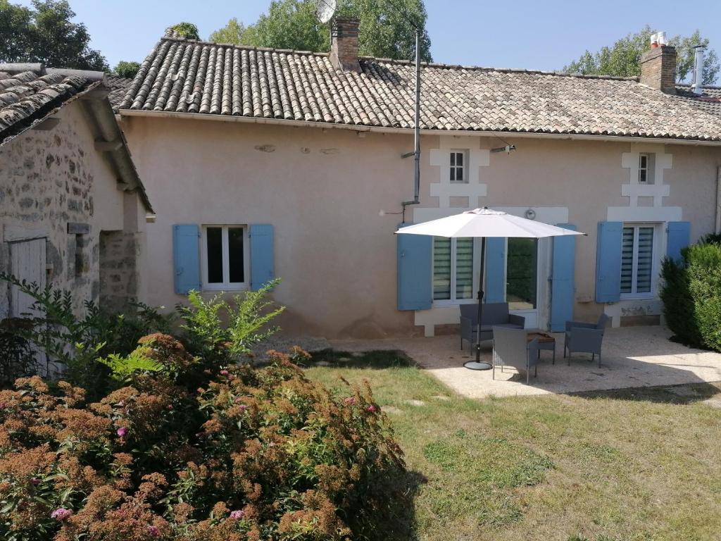 a house with an umbrella and a table and chairs at Gite La Passerelle de Giez - Vienne (86) Poitou-Charentes in Marigny-Chemereau