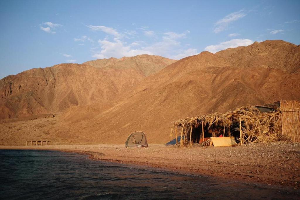 Tienda de campaña en una playa con montañas al fondo en Fully equipped Remote off-grid Solar Wooden Home, en Dahab