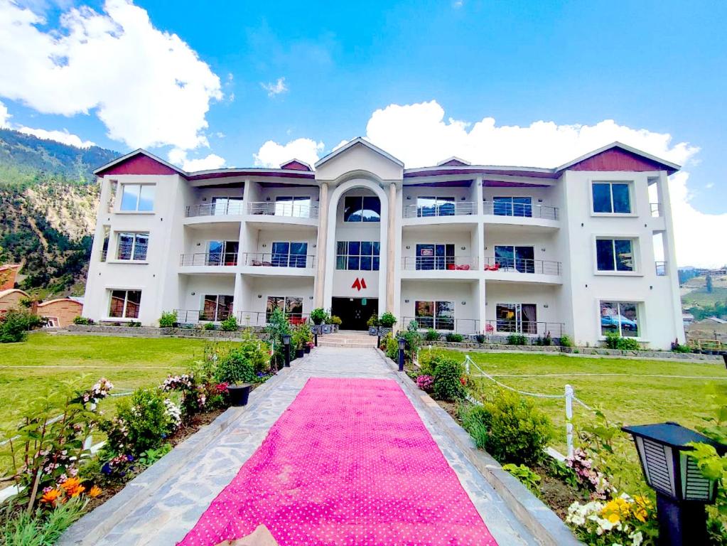 un gran edificio blanco con una alfombra rosa delante de él en Maria Hotel and Resorts, en Kalām