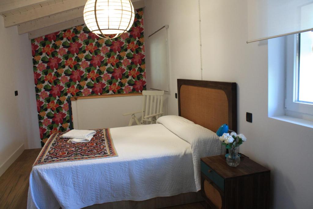 - une chambre avec un lit et un vase de fleurs dans l'établissement Loft La buena vida, à Peñaranda de Duero