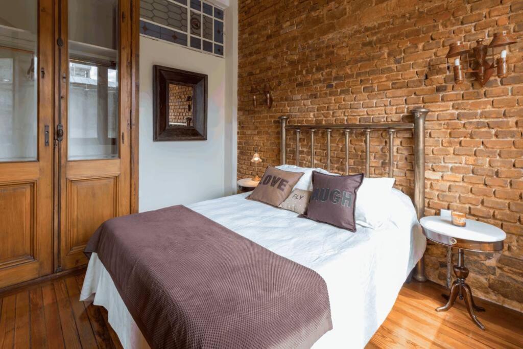 um quarto com uma cama com uma parede de tijolos em The Wall Montevideo [001] Live in The Old Town em Montevidéu
