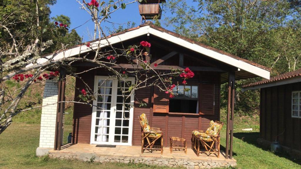 une petite maison avec 2 chaises et une terrasse couverte dans l'établissement Chalé Hibisco Amarelo, à Juquitiba