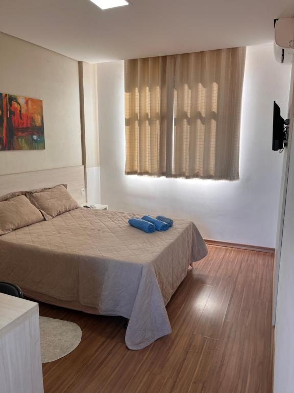 a bedroom with a bed with two blue shoes on it at Suíte Leshalles 311 - no Paris Residencial Service in Lagoa Santa