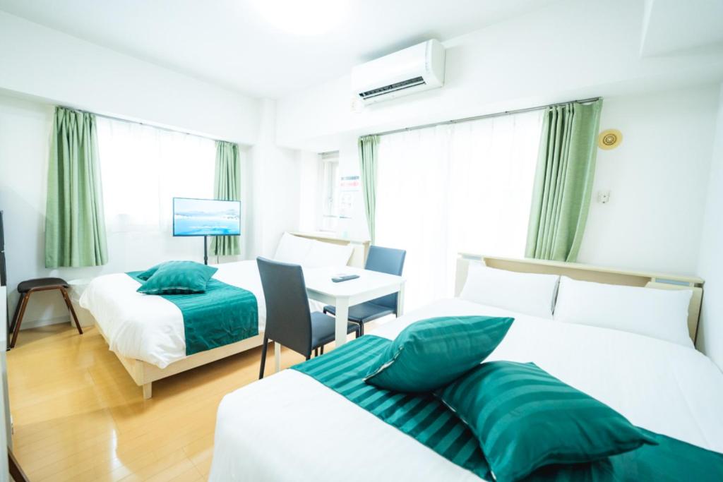 a hotel room with two beds and a desk at Smart Vacation Canaan A スマートバケーション　カナン A in Kagoshima