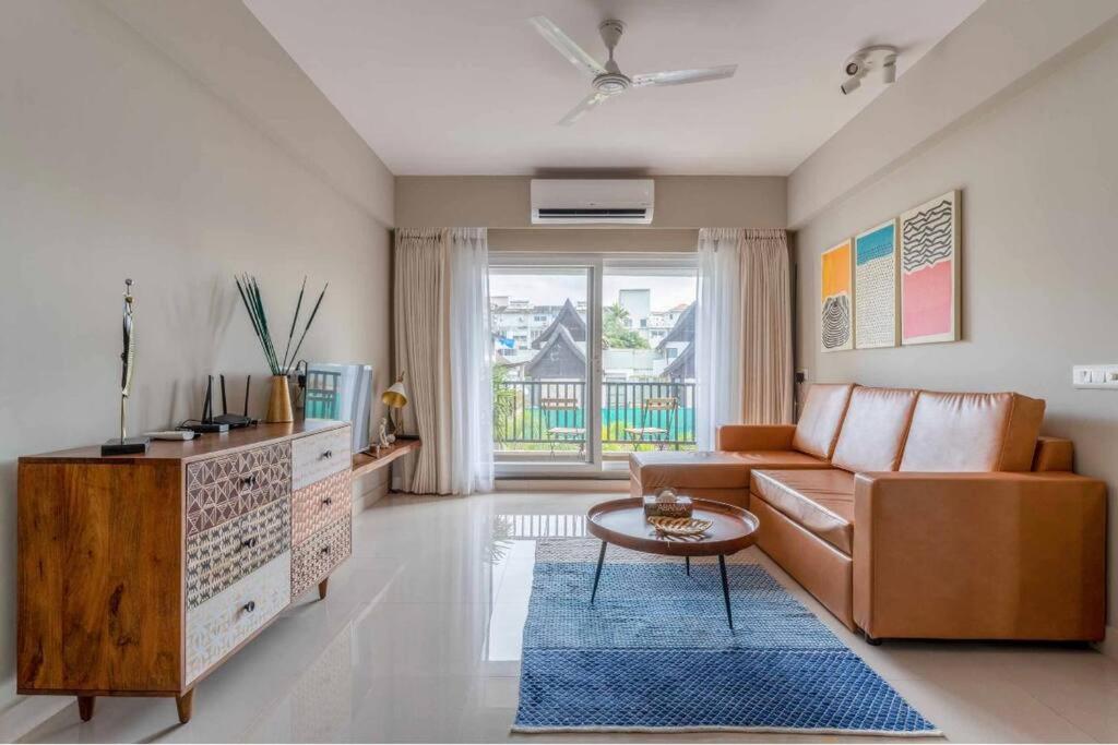 a living room with a couch and a table at Ripples:Pool facing/RiverView/7 mins to Coco Beach in Nerul