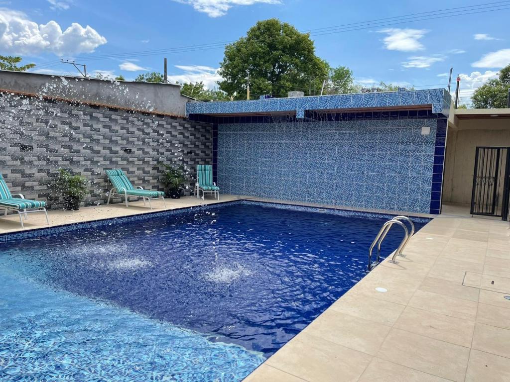 einen Pool mit zwei Stühlen und einer Ziegelwand in der Unterkunft Casa Hotel Estelar in Villavieja