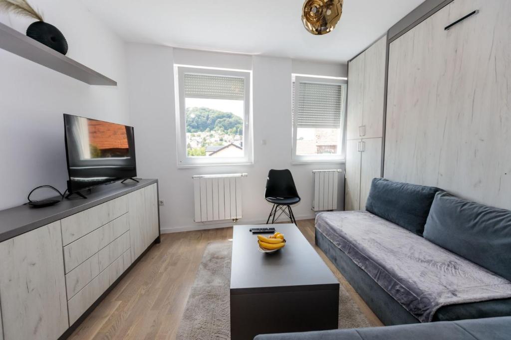 a living room with a couch and a tv at Apartman Skver in Tuzla