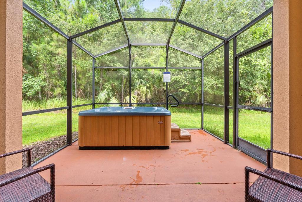 a hot tub in a greenhouse with a view of a forest at Hot Tub included 4 BR at Regal Oaks RO2761N in Kissimmee