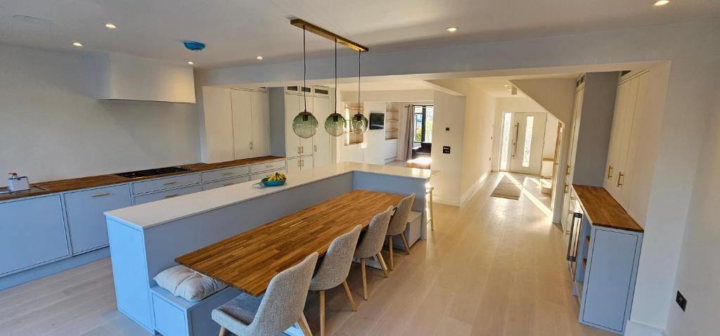 ニューキーにあるLuxury home near Fistral Beachのキッチン(長い木製テーブル、椅子付)