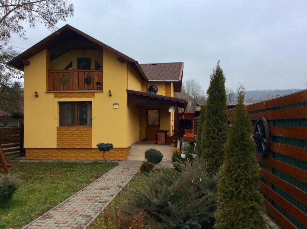 a yellow house with a balcony and a fence at Casa Odihnei Villa & Tiny-House in Tîrnăveni