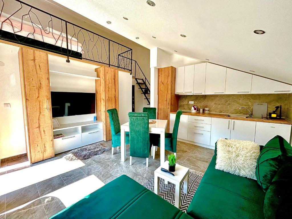 uma sala de estar com um sofá verde e uma cozinha em Apartman Viny em Sokobanja