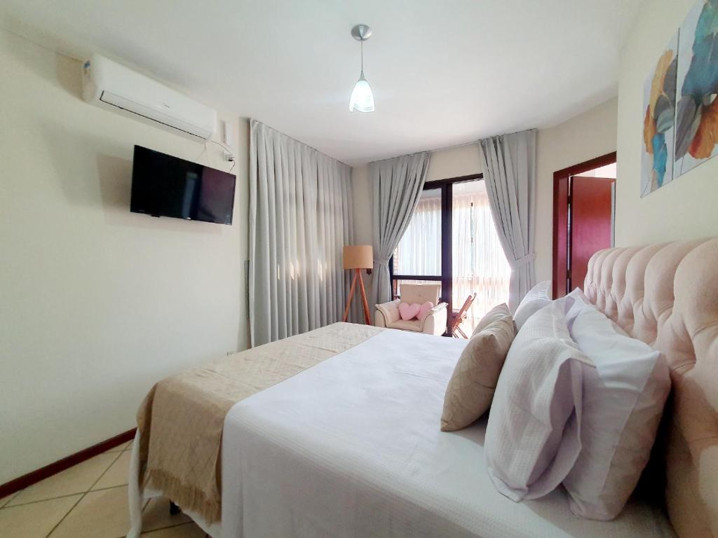 a bedroom with a bed and a television in it at Pousada Estrela Mares in Guarda do Embaú