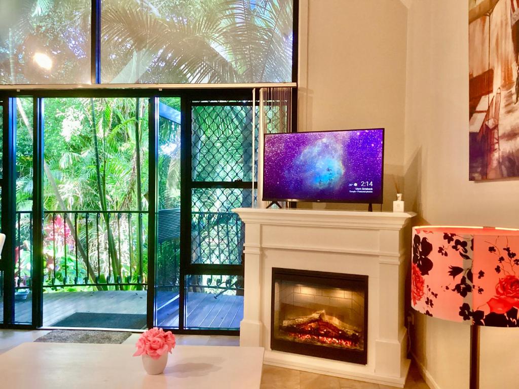 a living room with a tv and a fireplace at Romance Chalet on Gallery Walk with Spa, Fireplace, WiFi & Netflix in Mount Tamborine