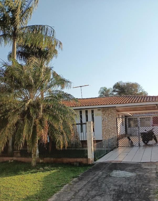 a house with a fence and a palm tree at Pousada Santa Felicidade Trieste D in Curitiba