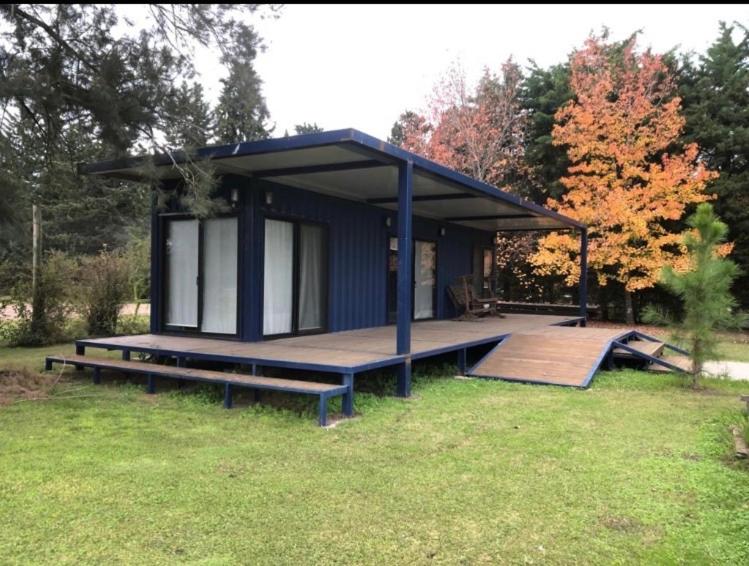 ein kleines blaues Haus mit einer Terrasse im Gras in der Unterkunft ONE TRIP in Paysandú