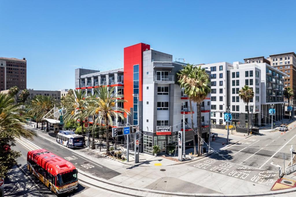 長灘的住宿－Hotel Mai Downtown Long Beach，一辆红色的巴士沿着城市街道行驶,街道上有许多建筑