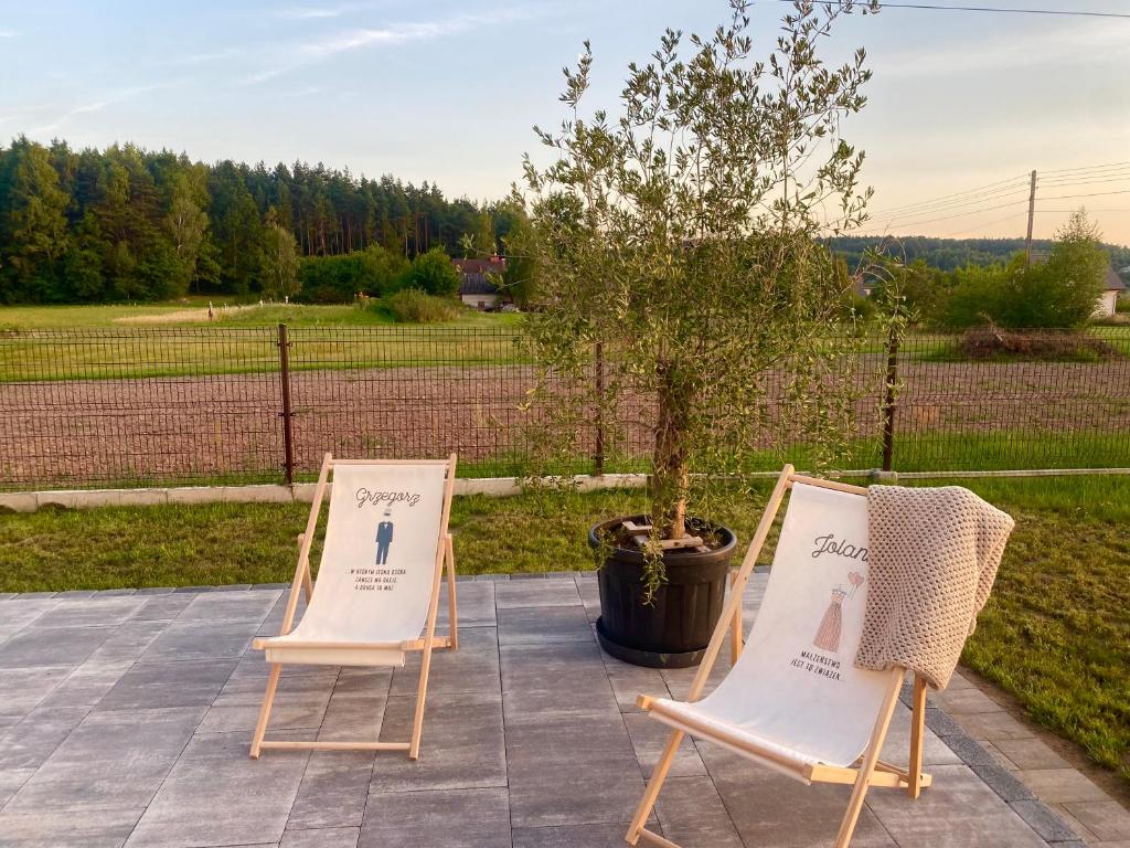 two chairs sitting on a patio next to a tree at Apartamenty na Wzgórzu Boho in Zagnańsk