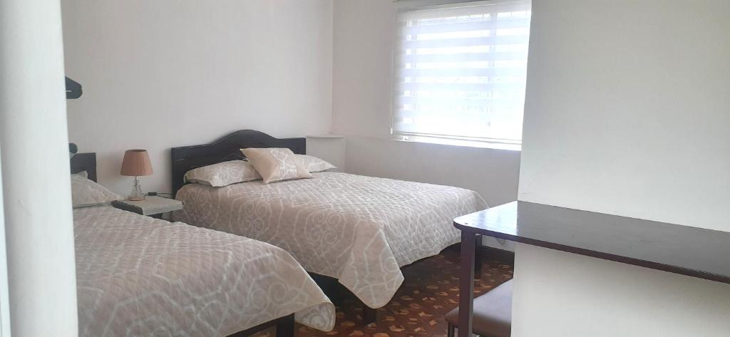 um pequeno quarto com 2 camas e uma janela em MI ESTANCIA HOSPEDAJE em Cuenca