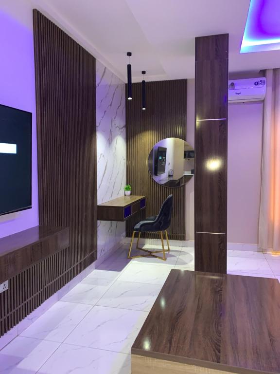 a lobby with a chair and a television in a room at Executive Royal Suite Kado in Abuja