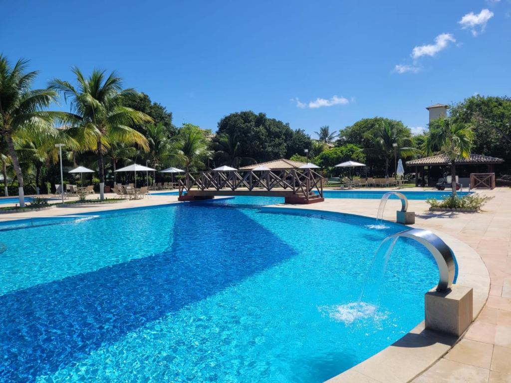 ein Schwimmbad mit blauem Wasser in einem Ferienort in der Unterkunft Genipabu Club House Guarajuba Camaçari-Ba in Camaçari