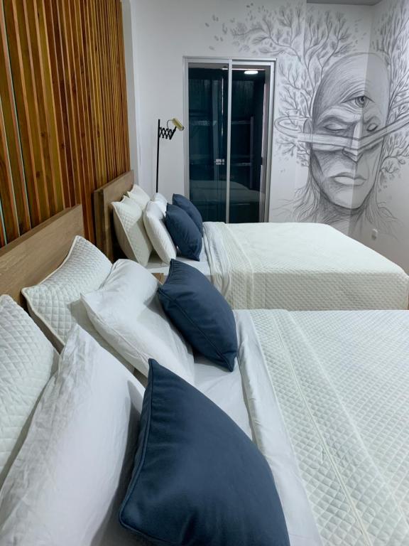 Roldanillo的住宿－Hotel Cocli，一间带三张床的卧室和一张女人的壁画