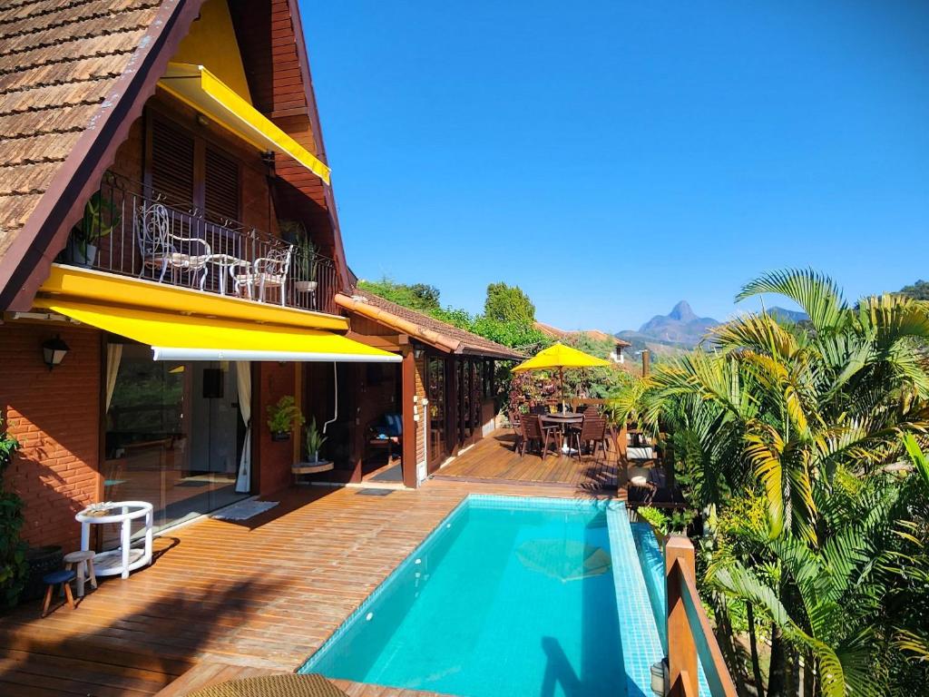 ein Haus mit einem Pool und einer Terrasse in der Unterkunft Casa Serrana, 4 quartos com ar e piscina aquecida em meio à Natureza de Itaipava in Itaipava