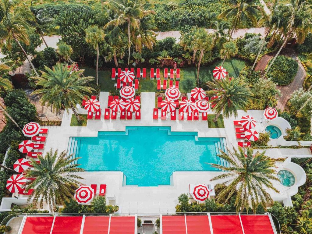 een luchtzicht op een zwembad van het resort met rode en witte parasols bij Faena Hotel Miami Beach in Miami Beach