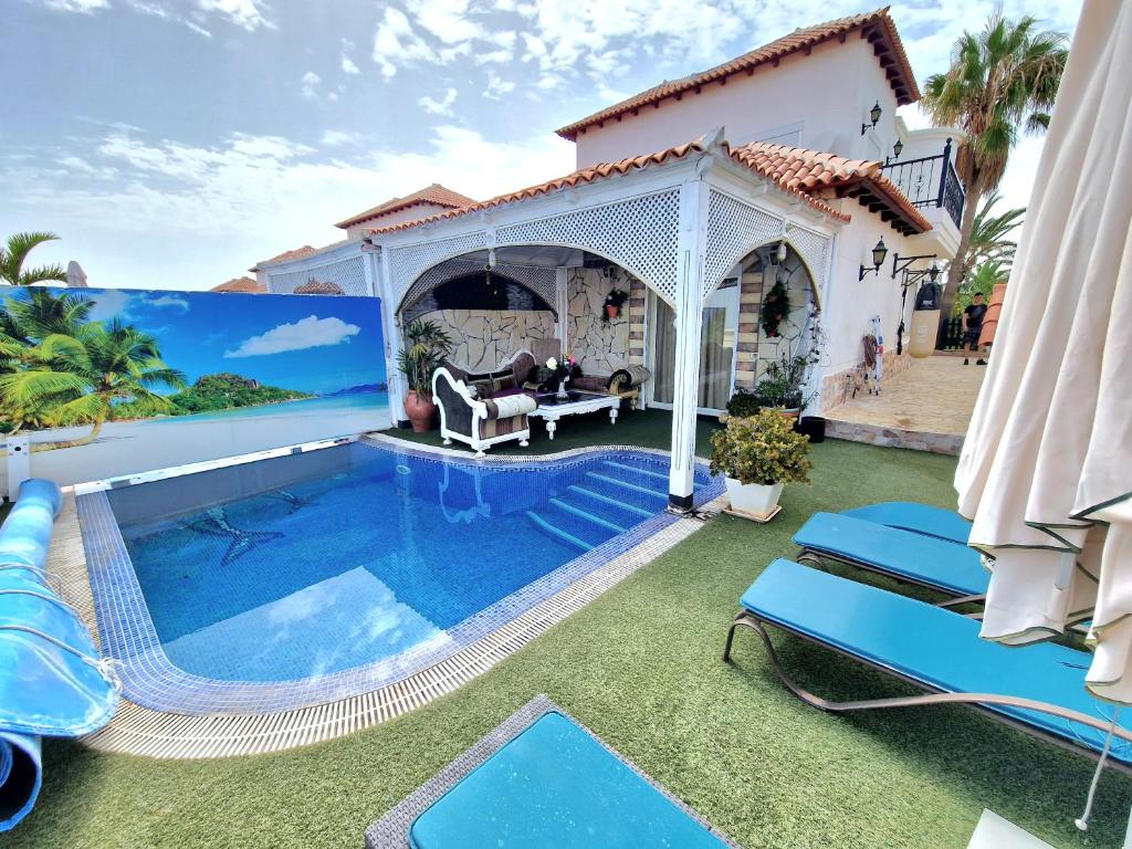 un patio trasero con piscina y una casa en Villa Habibi Luxury 5A, en Chayofa