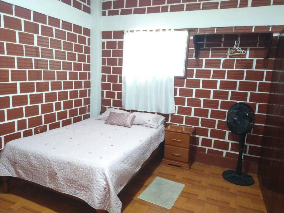 um quarto com paredes de tijolo, uma cama e uma janela em Casa personal o familiar para vacacionar en Yurimaguas em Yurimaguas